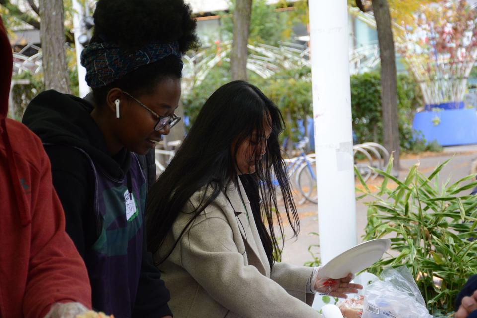 Two volunteers plate food side by side at the serving table.