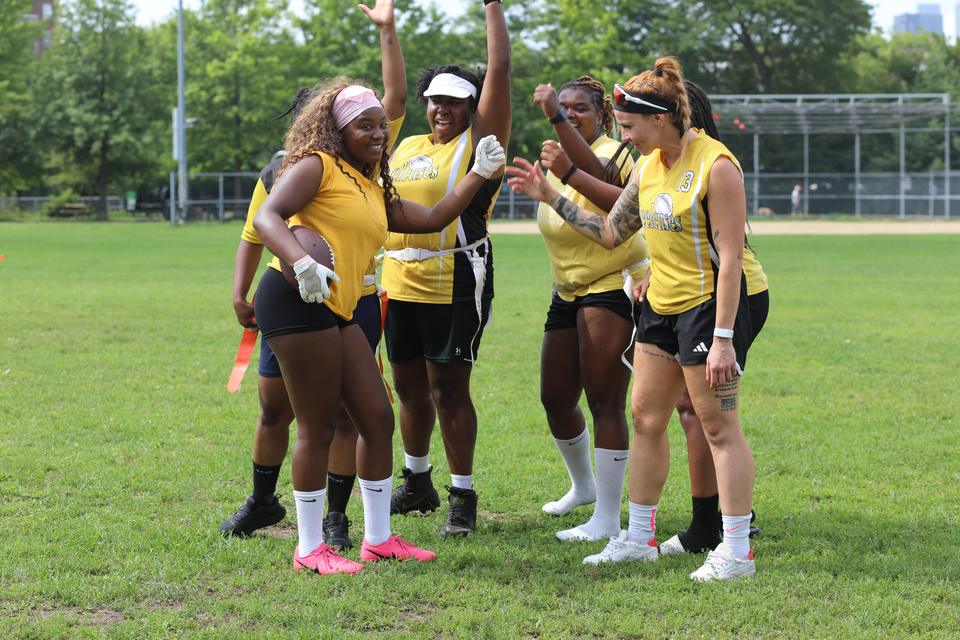 A team in yellow celebrates on the field, arms raised.